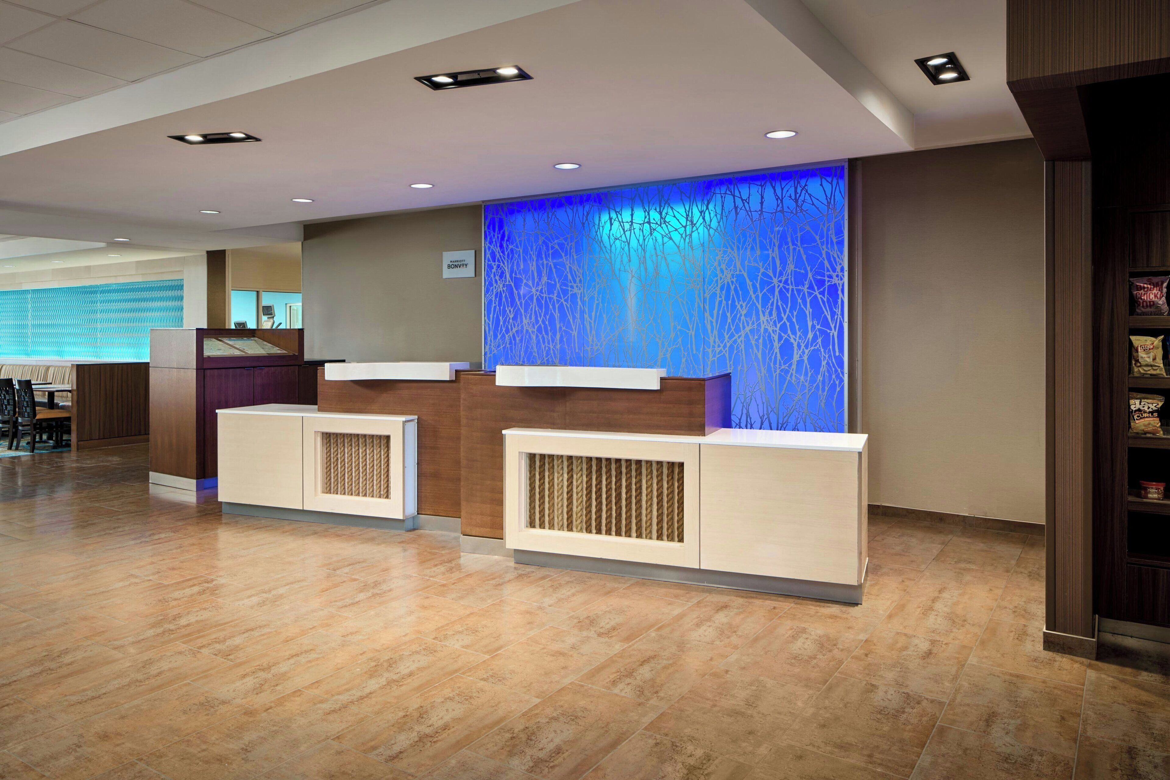 A hotel reception area with a modern design, featuring a reception desk, a seating area, and a decorative wall with a blue pattern.