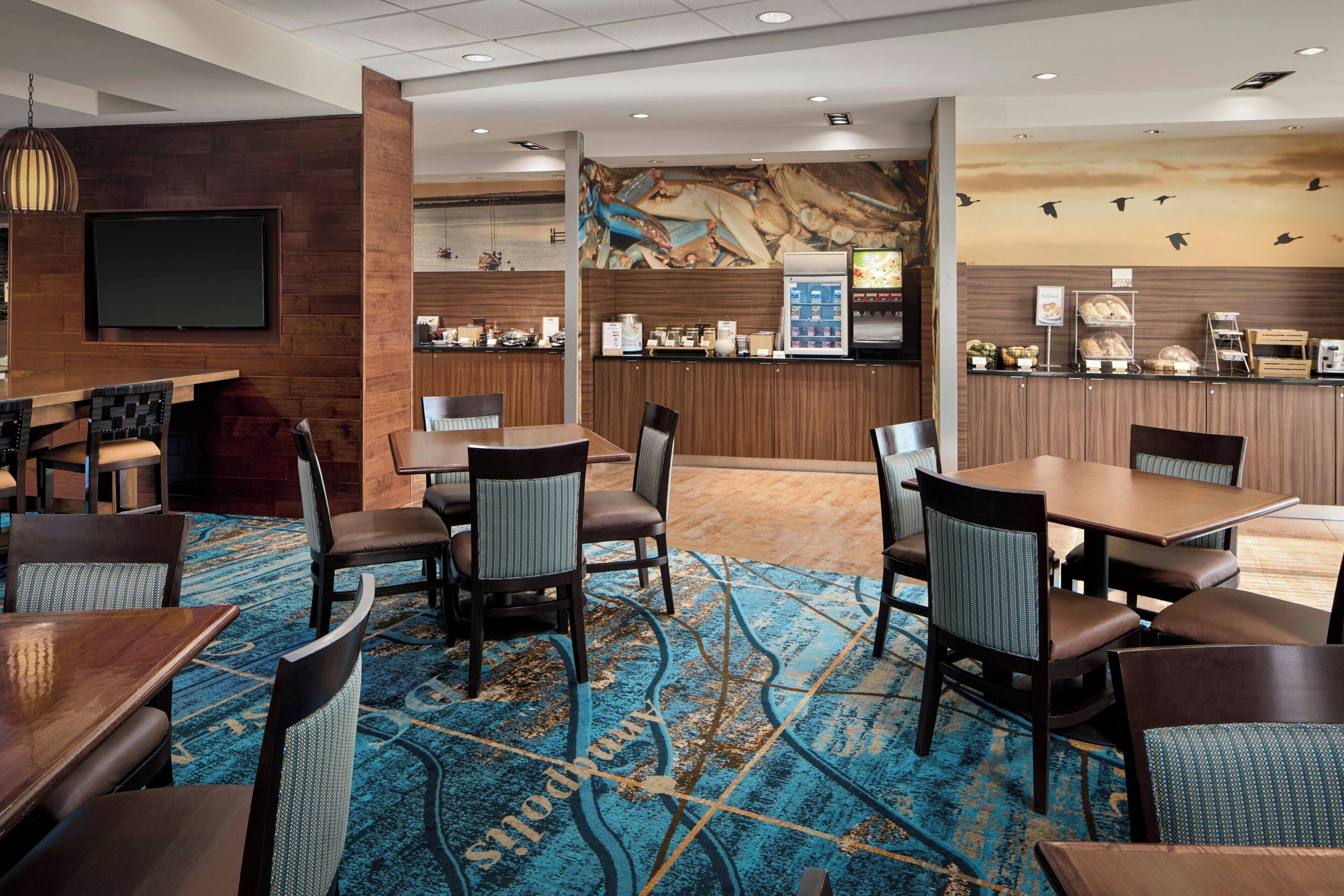 A hotel lobby with a bar area, seating arrangements, and a large screen.
