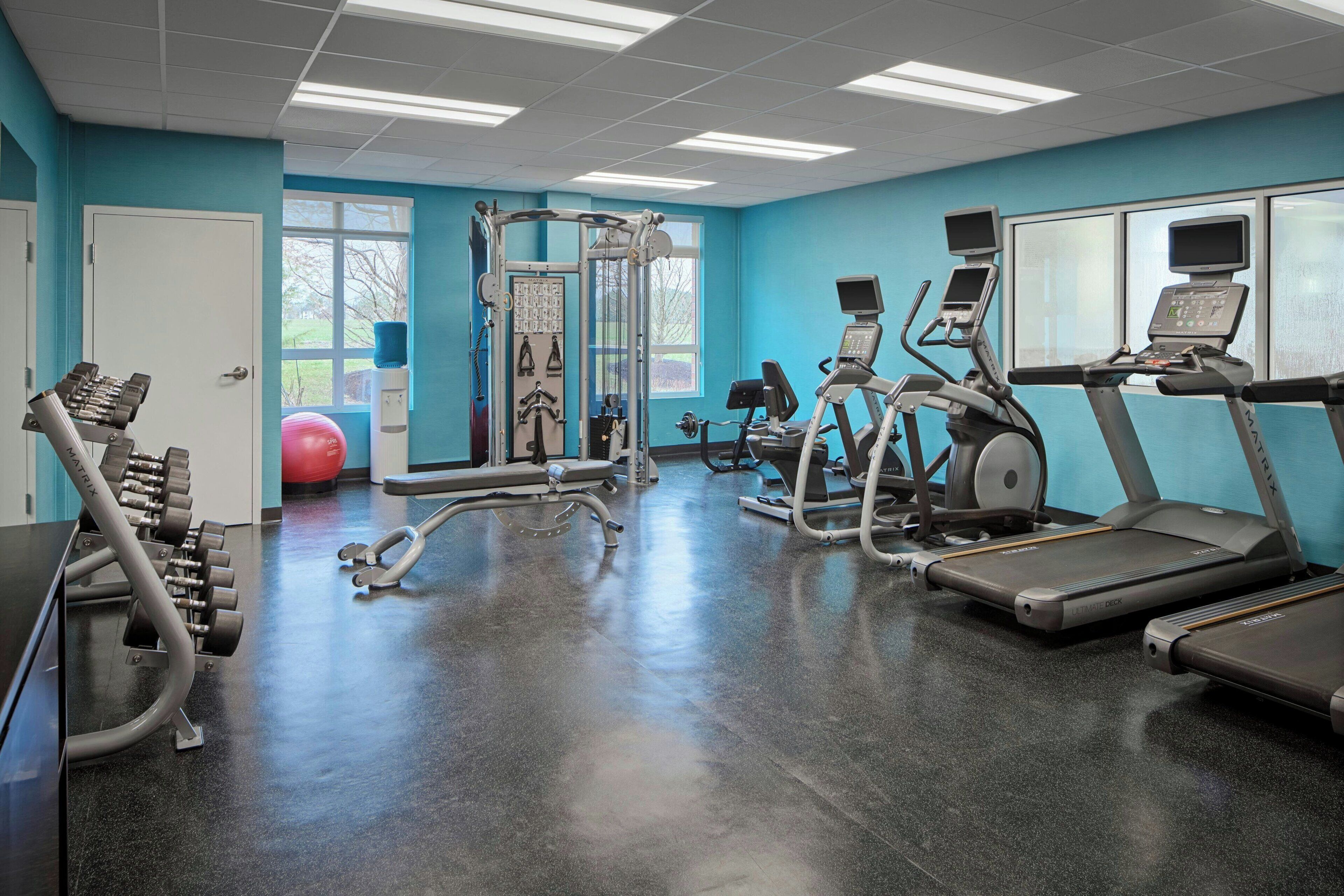 A gym with exercise equipment, a water dispenser, and a large window.