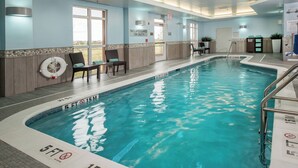 An indoor swimming pool with clear water, marked depth lines, and a lifeguard chair.