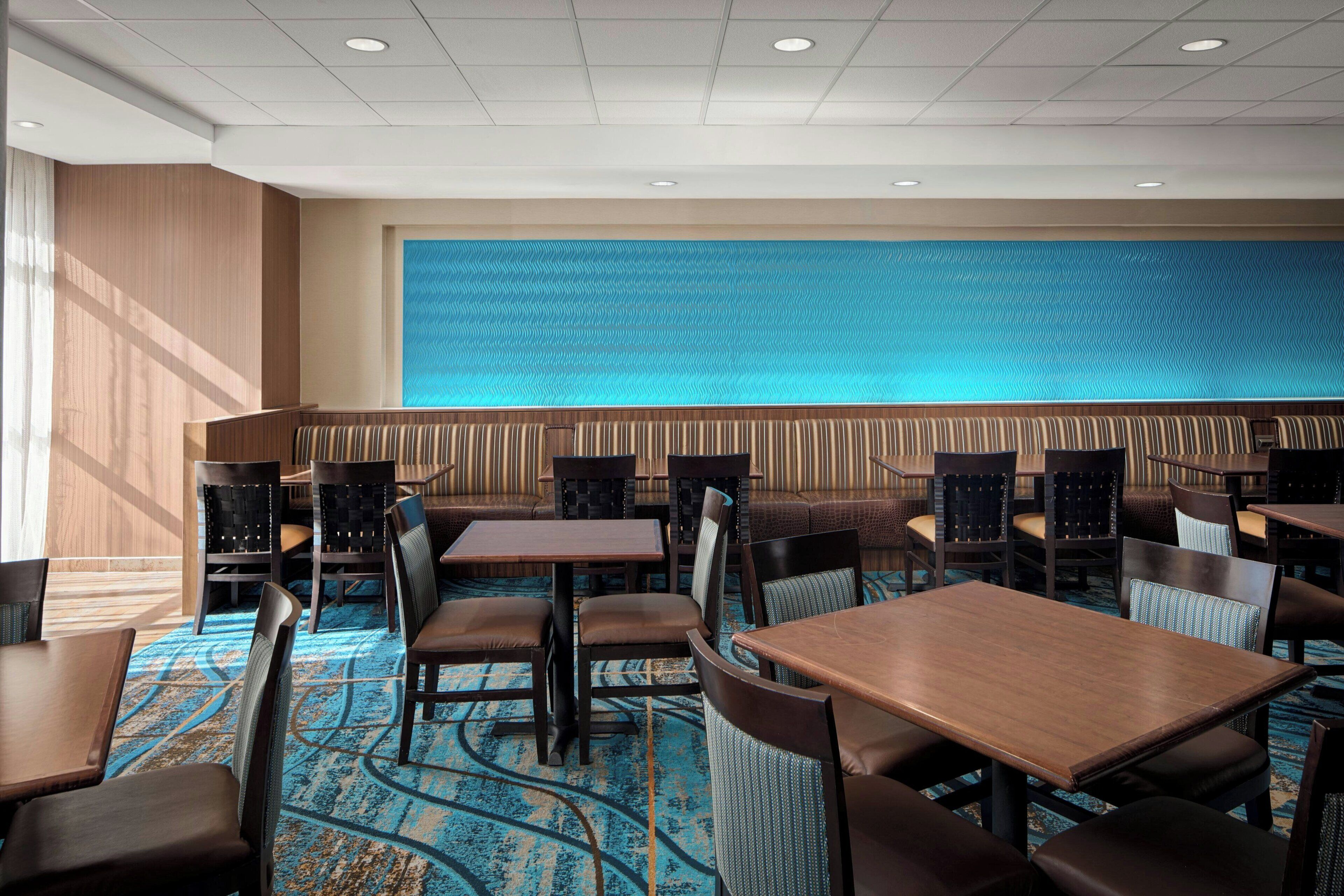 Un vestíbulo de hotel con una pared azul con textura, paneles de madera y una alfombra estampada.