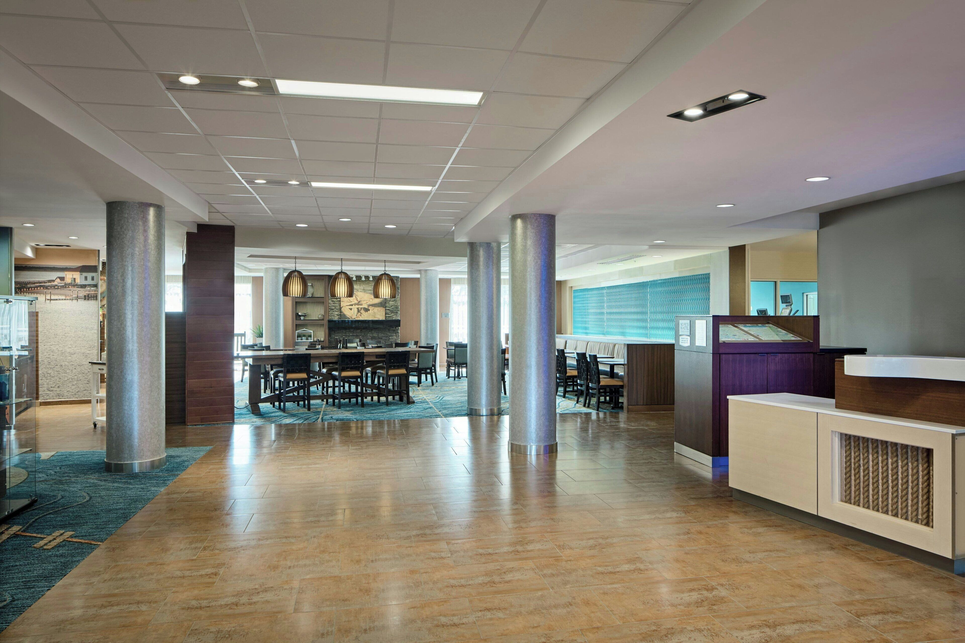 A spacious lobby with a central seating area, a reception desk, and a view of the dining area.
