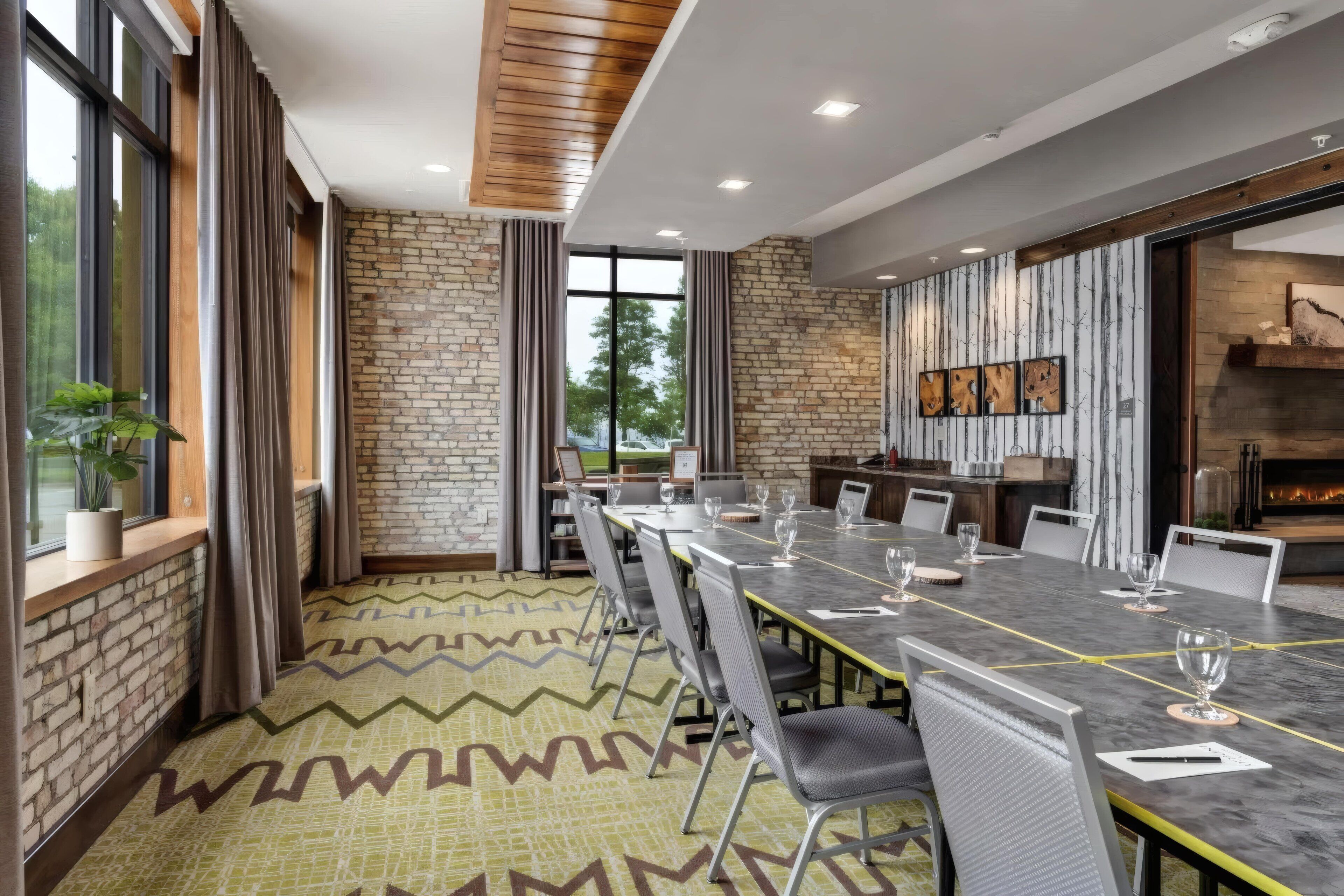 A conference room with a long table, chairs, and a brick wall.