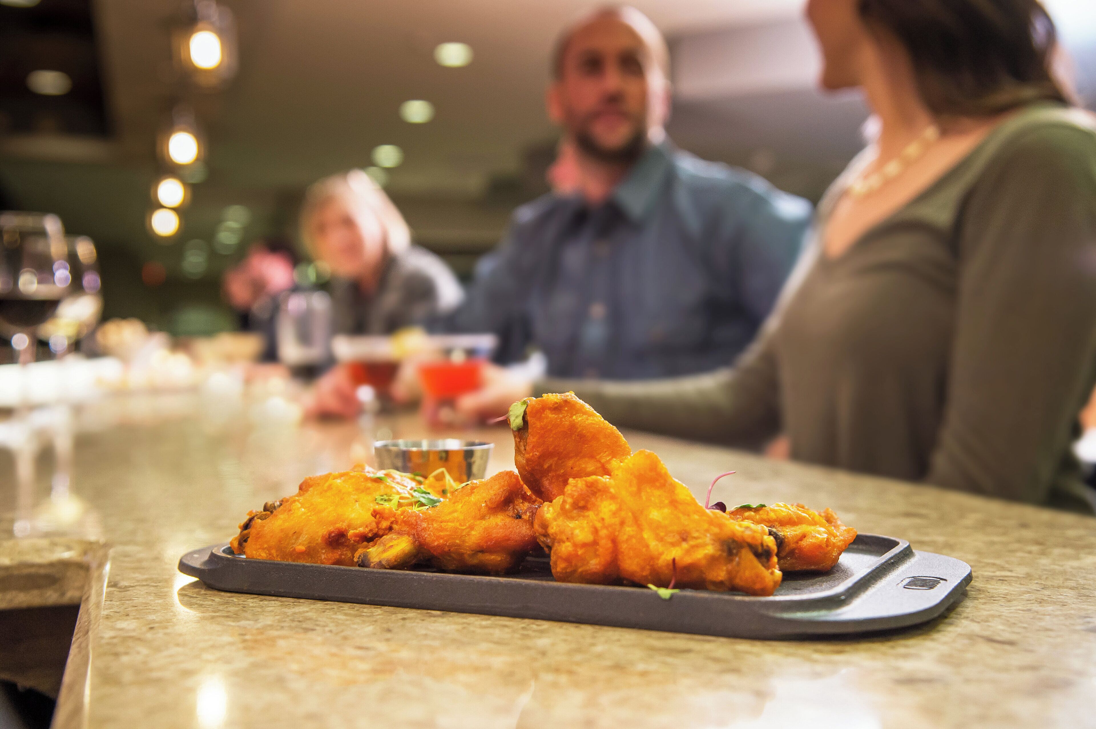 A dining table with a plate of food, a glass of beverage, and a metal tray.