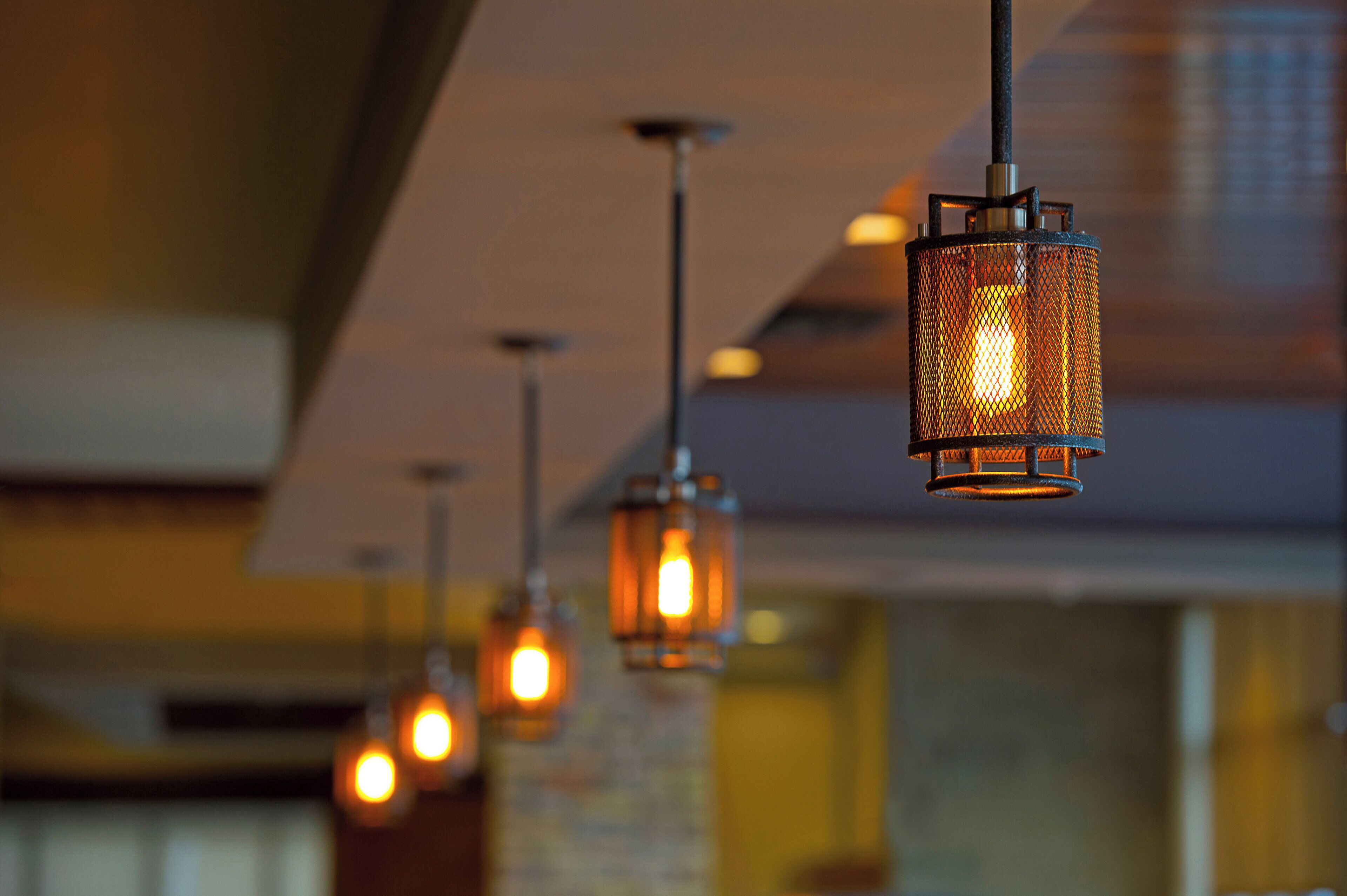 A row of hanging pendant lights with a warm glow, suspended from a ceiling with a modern design.