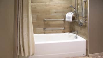 Una bañera con panel de pared de madera, una barra de apoyo y un perchero.