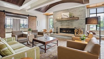 A spacious living room with a fireplace, comfortable seating, and large windows offering views of the outdoors.