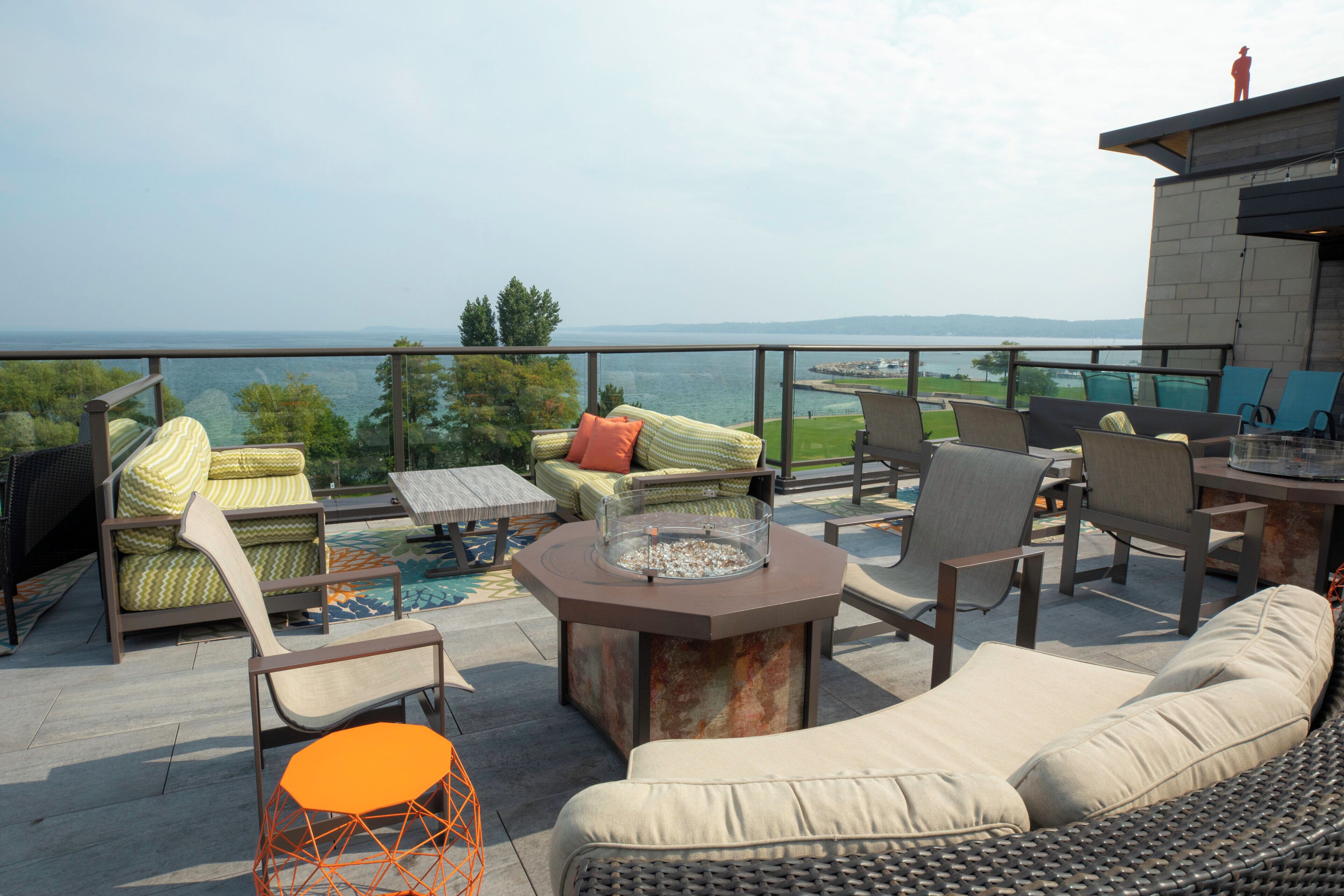An outdoor seating area with a view of the water, including a sofa, chairs, and a table.