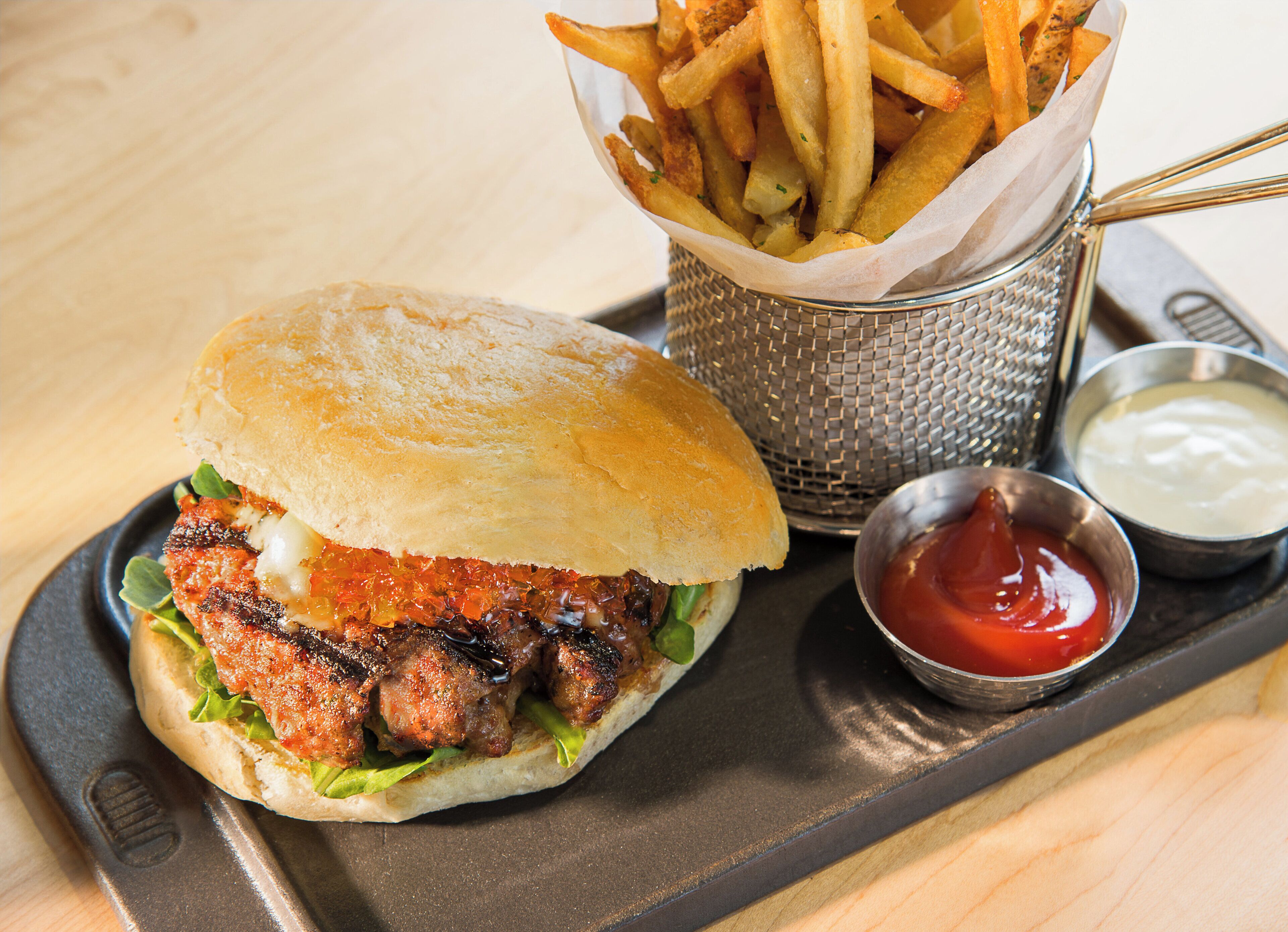 Un hamburger accompagné de frites et de ketchup, le tout servi sur un plateau.