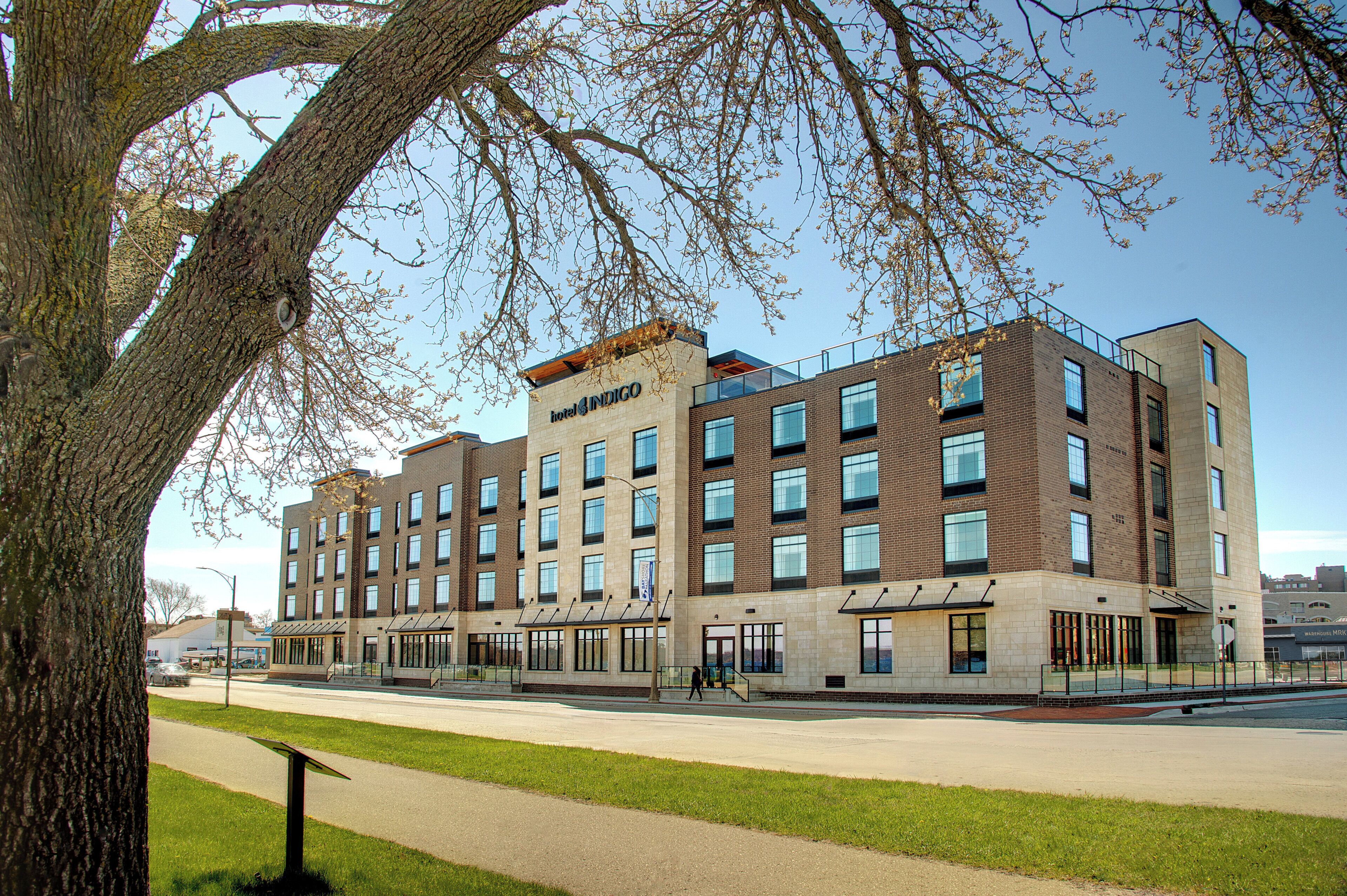 A hotel with multiple floors, a flat roof, and a sign that reads 'hotel INDIGO.'