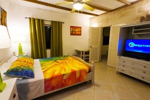 A bedroom with a bed, a television, a desk, and a chair. - Yellow Bird Apartment (Silver Sands)