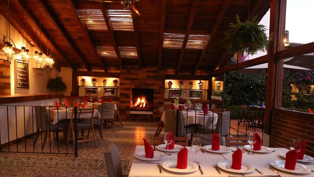 Un restaurante con vigas de madera, chimenea y mesas preparadas para comer.