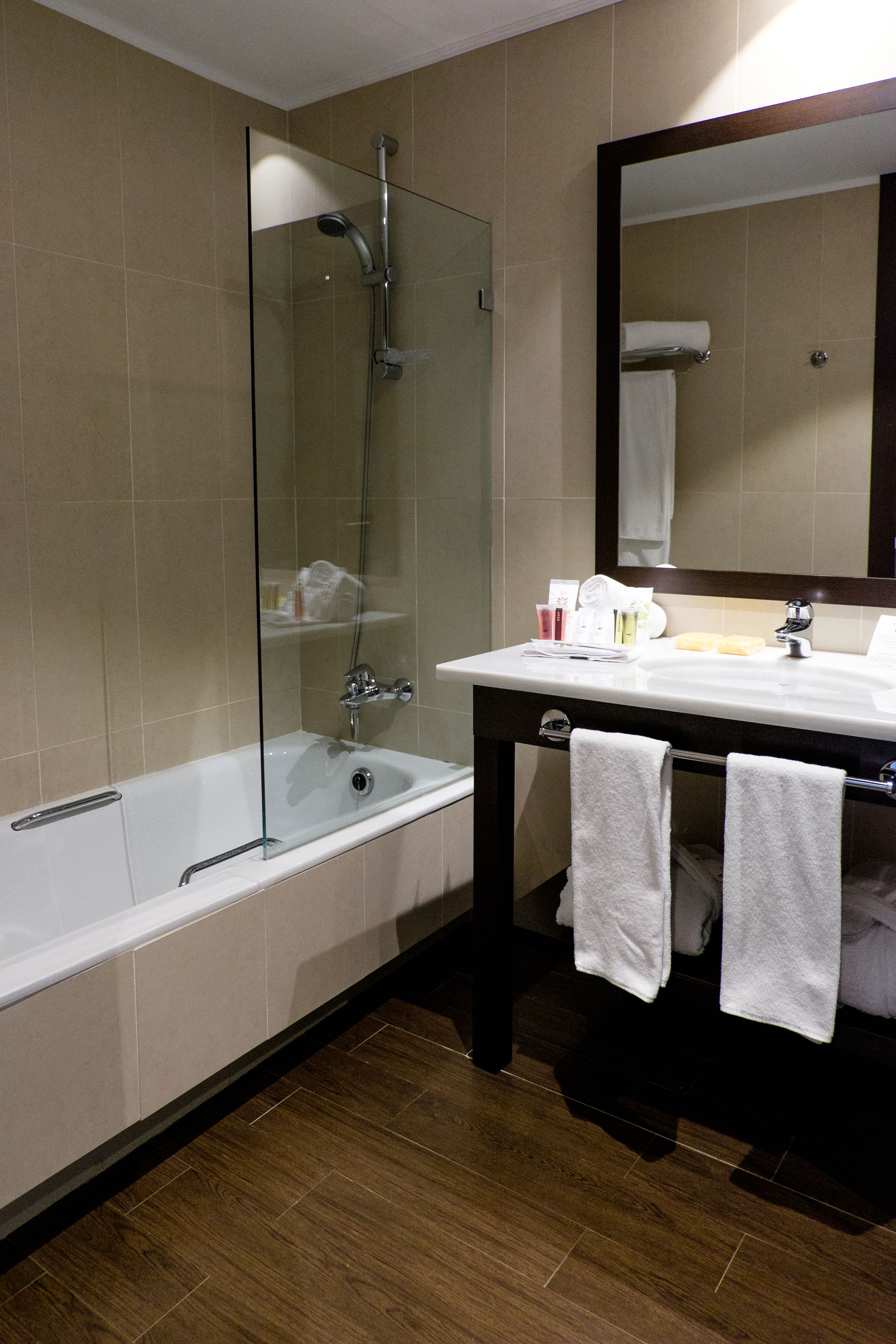 A modern bathroom with a glass-enclosed shower, a white sink, and a dark wooden vanity.