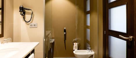 A bathroom with a shower, toilet, and hairdryer on the wall.