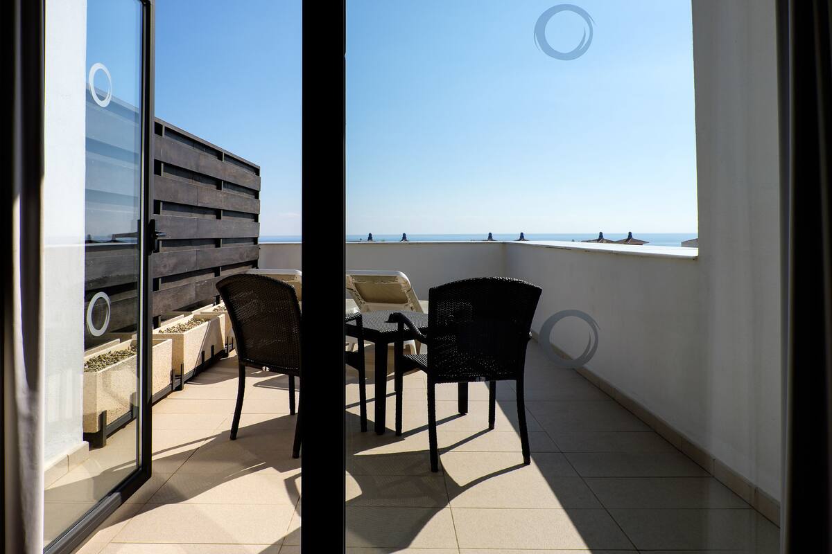 Un balcon avec vue sur la mer, une table et deux chaises.
