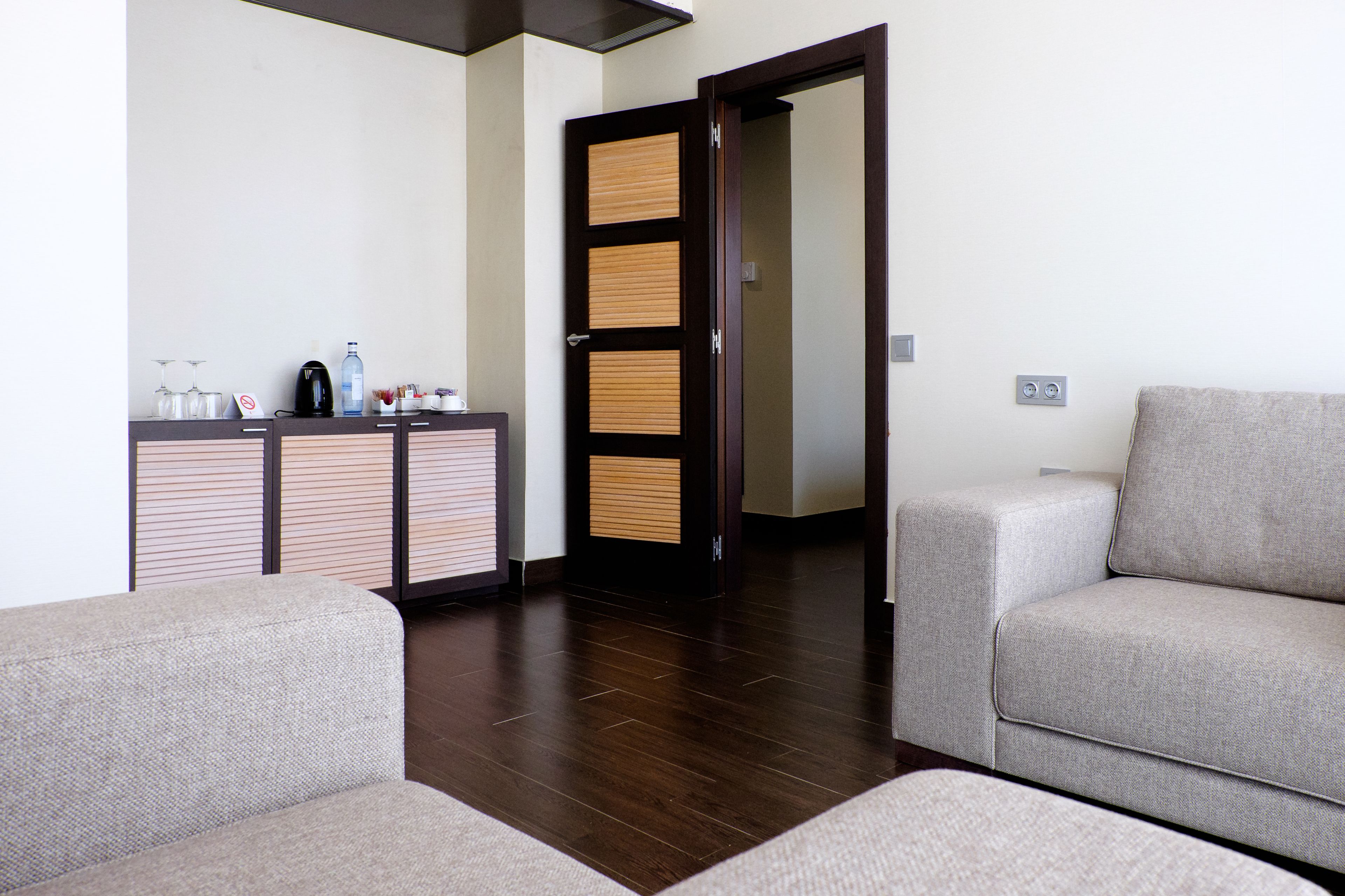 Ein modernes Wohnzimmer mit einer Couch und einem Schrank, in dem ein Kaffeeautomat steht.