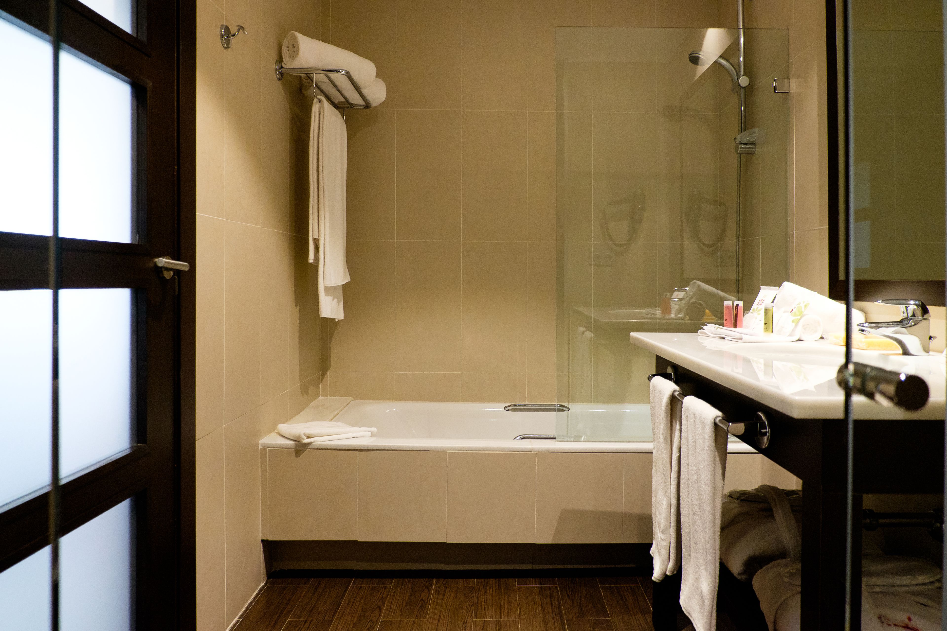 A modern bathroom with a bathtub, a glass shower enclosure, and a vanity with a mirror.