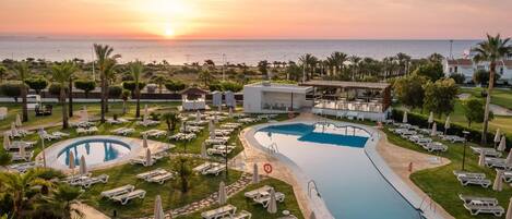 Una piscina al aire libre, sombrillas, sillones reclinables de piscina