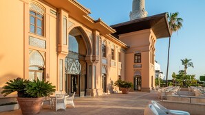 A building with a central dome, arched windows, and a courtyard with seating and potted plants.