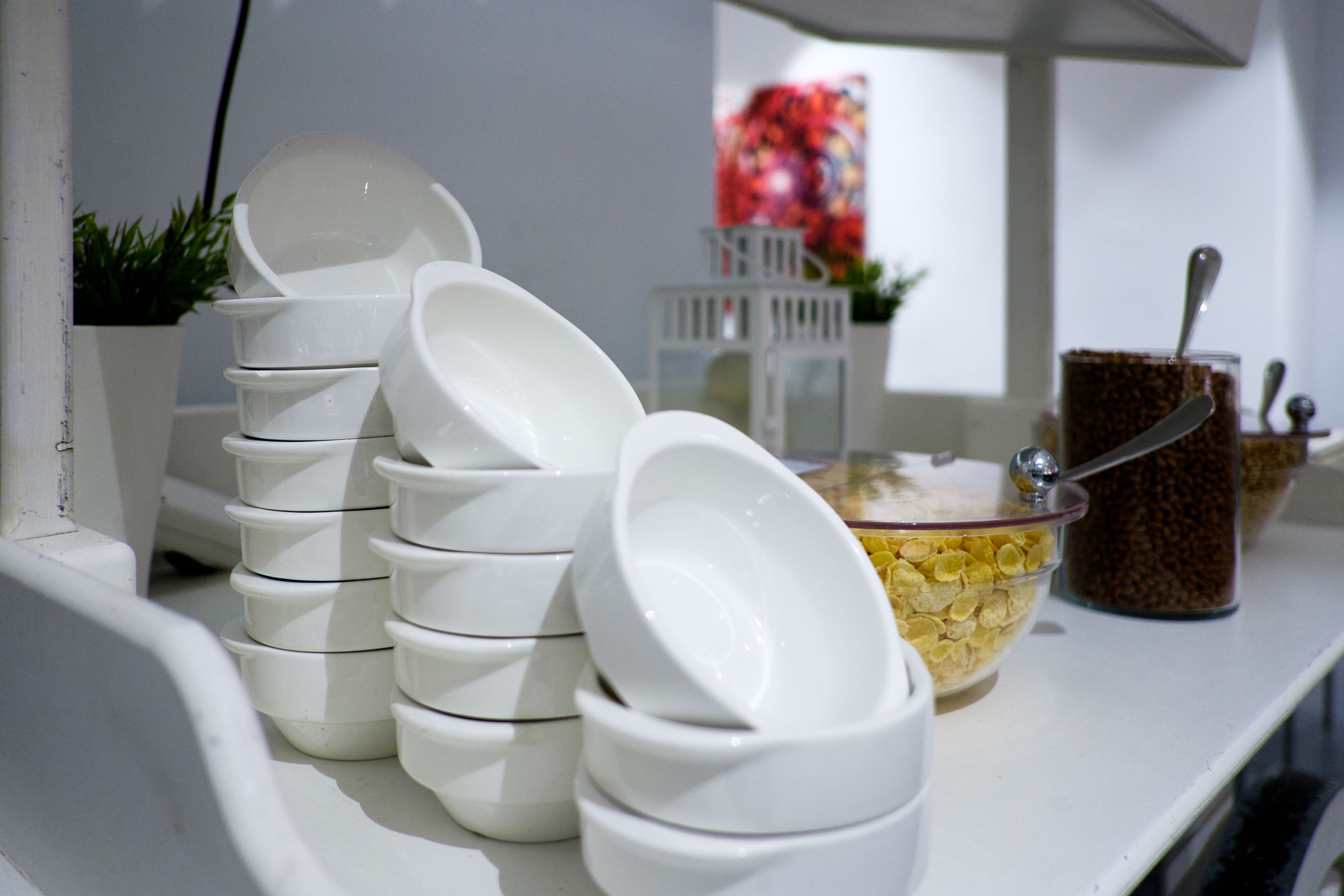 Un montón de tazones blancos y un tazón de cereal sobre una mesa blanca.