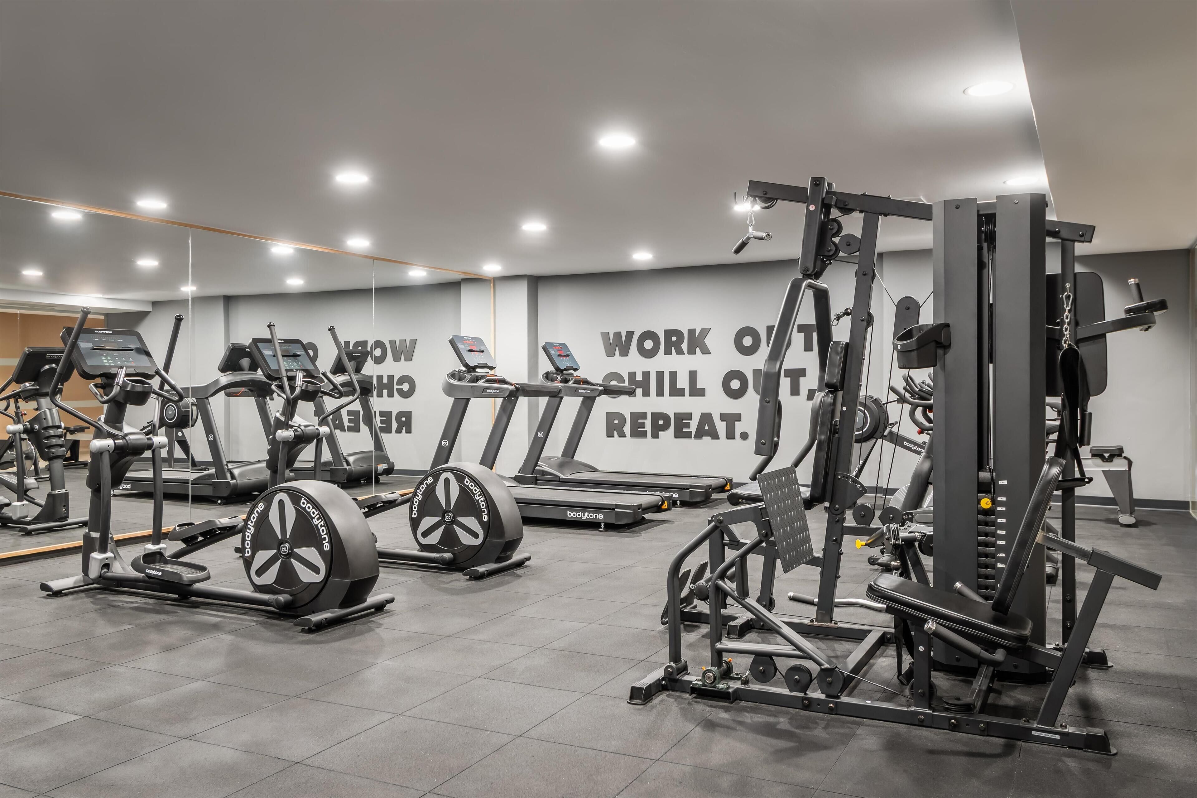 A gym with treadmills, elliptical machines, and weightlifting equipment.