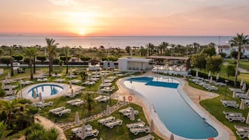 Una piscina al aire libre, sombrillas, tumbonas