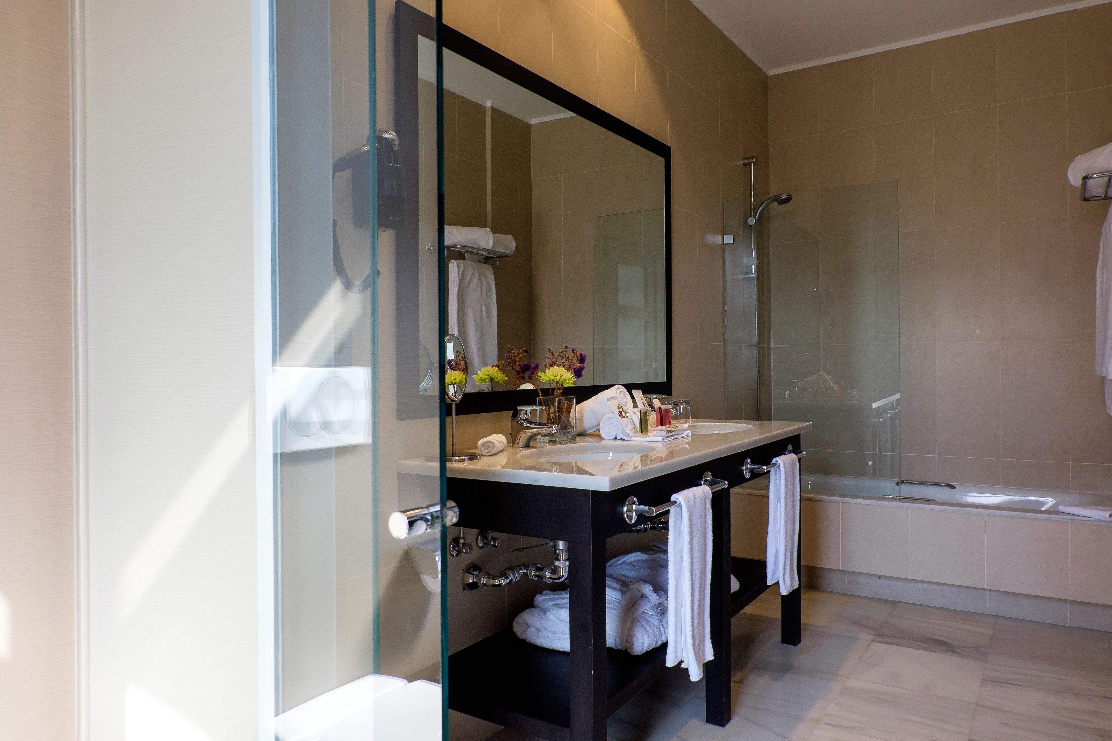 A modern bathroom with a glass-enclosed shower, a large mirror, and a bathtub.