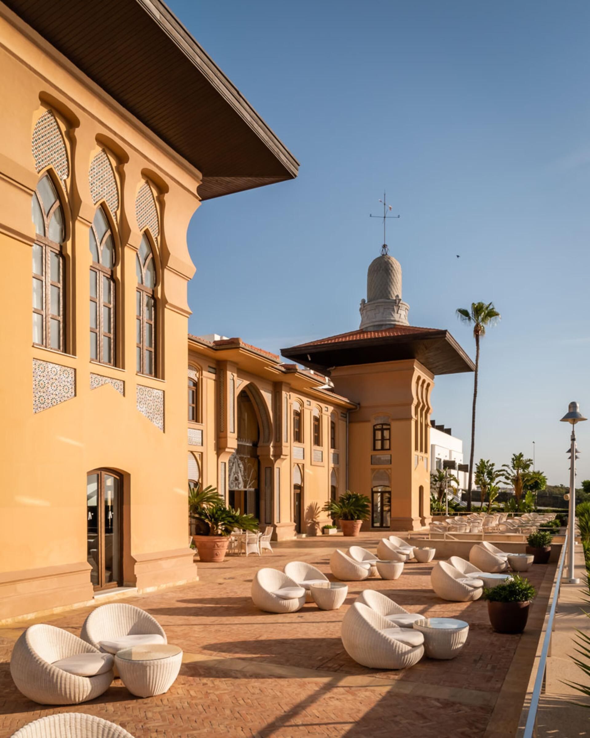 A courtyard with outdoor seating and a building with arched windows and a dome.