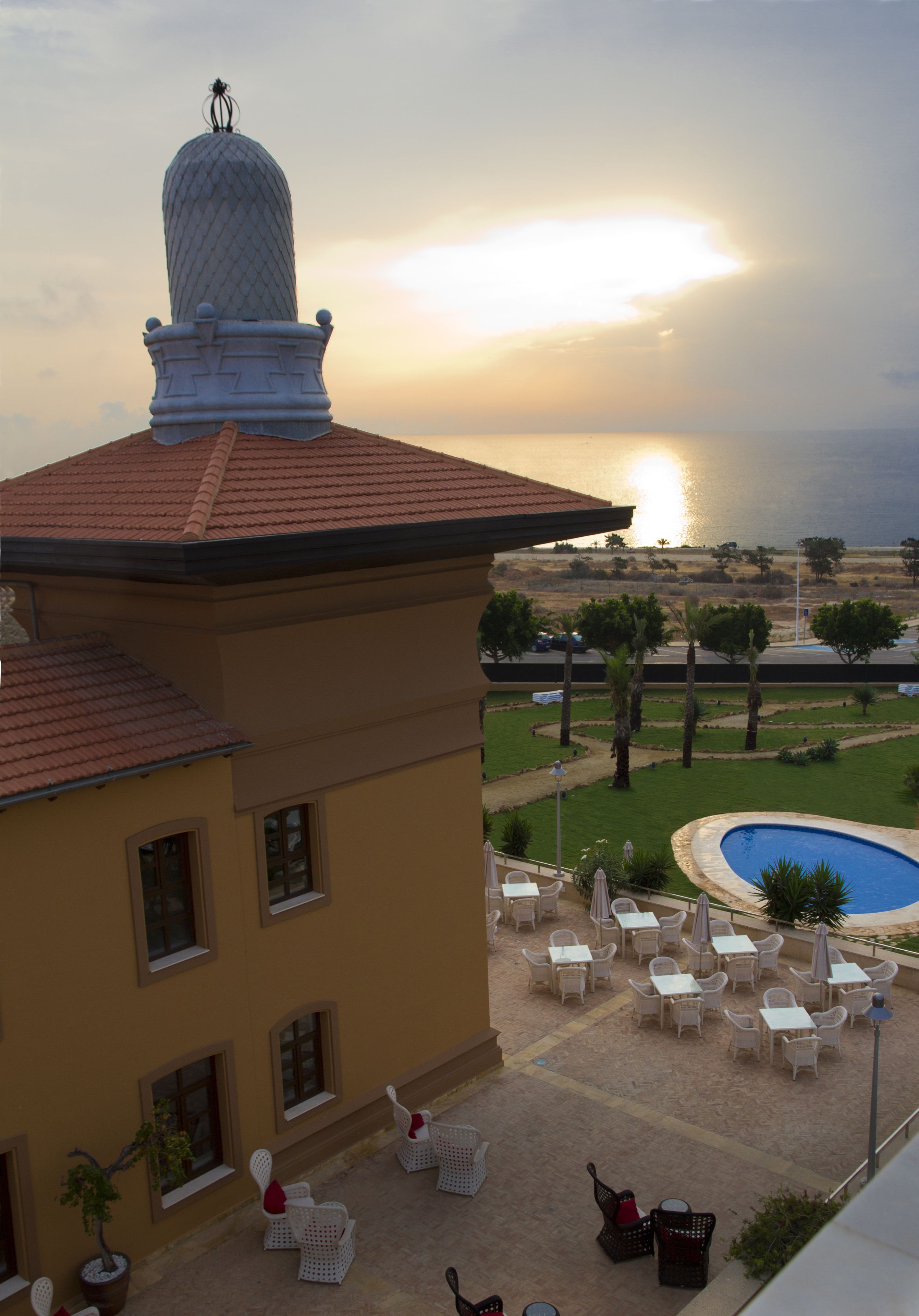 A building with a tiled roof, a swimming pool, and outdoor seating.