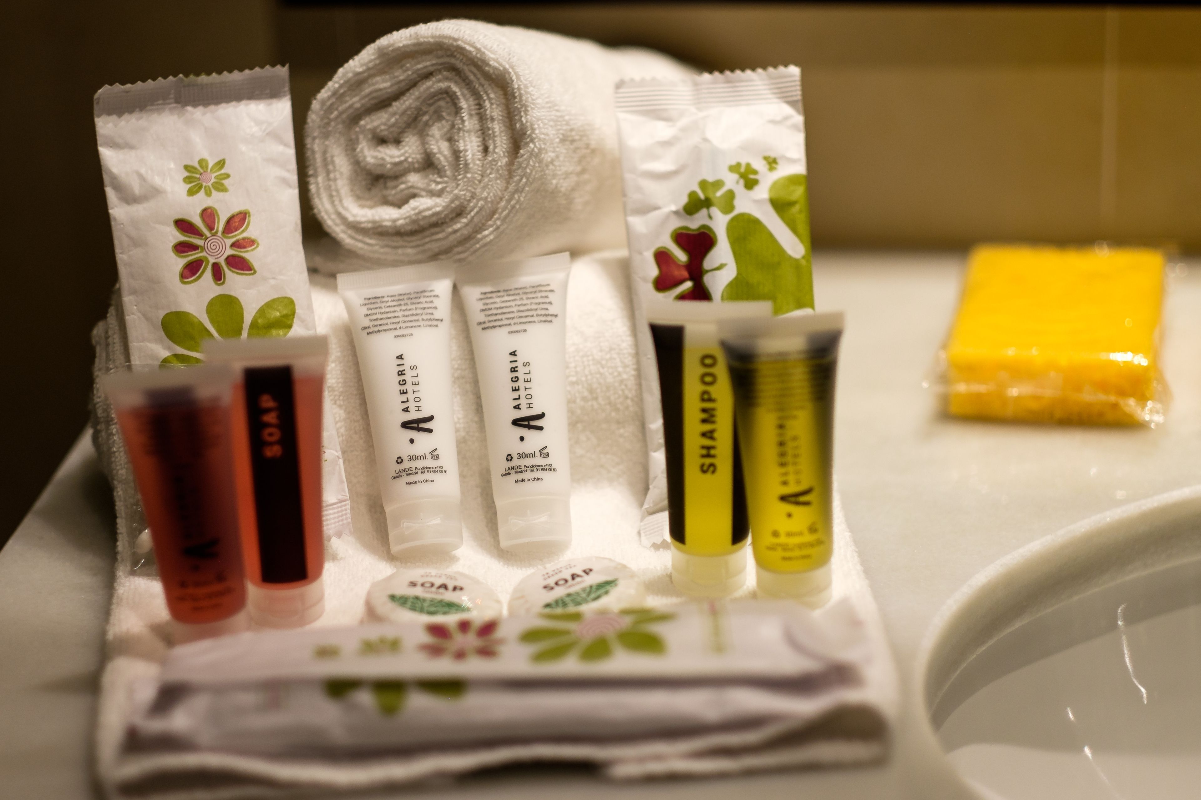Toiletries including shampoo, soap, and a towel arranged on a white surface.