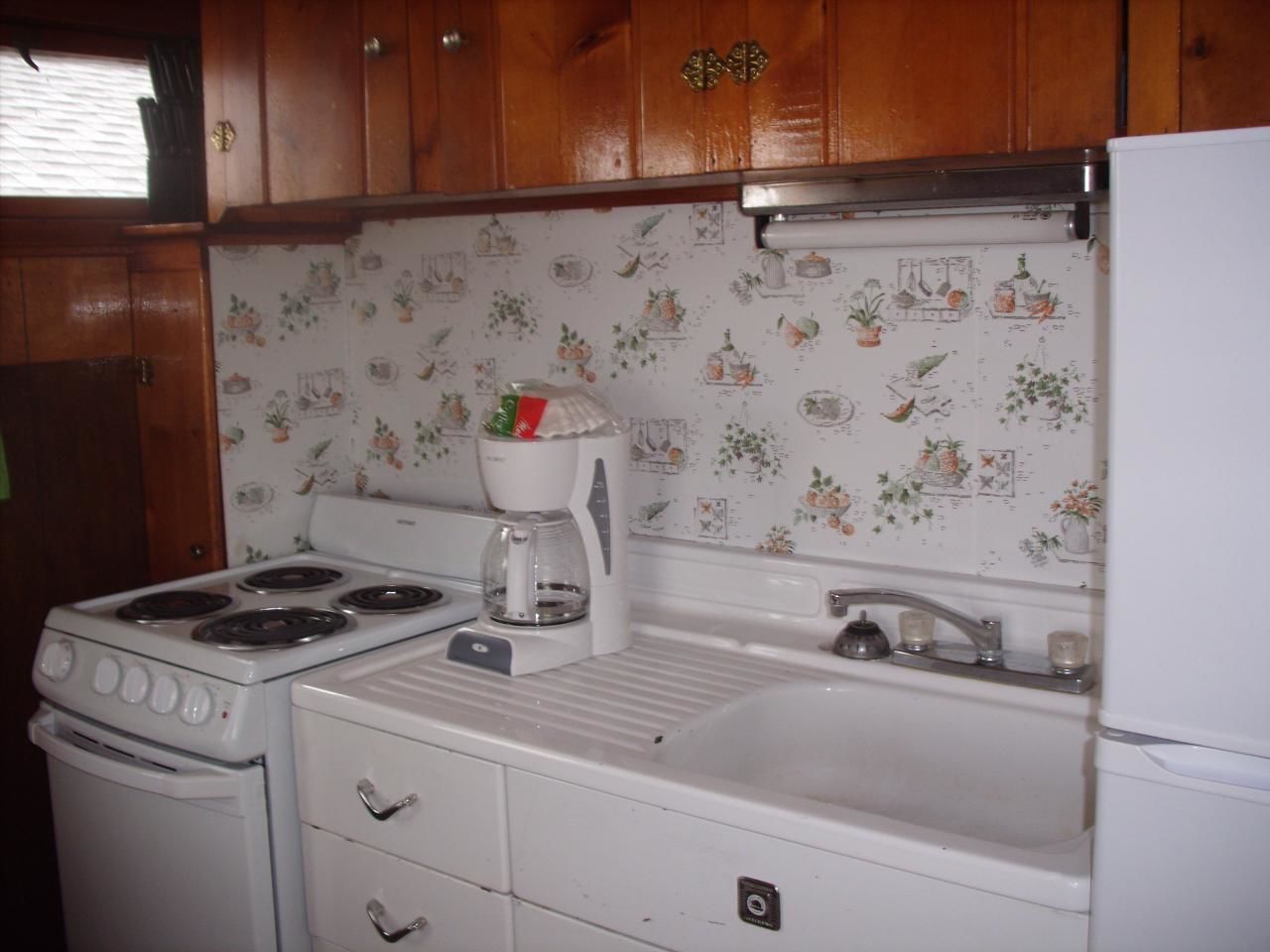 Une cuisine avec des meubles de rangement en bois, une cuisinière blanche, une machine à café et un évier.