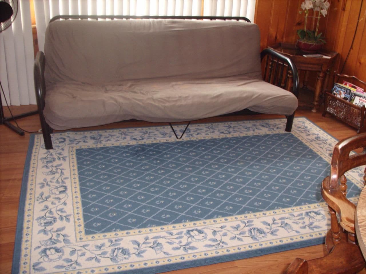 Een kamer met een bank, een kamerbreed tapijt, een houten tafel en een stoel.