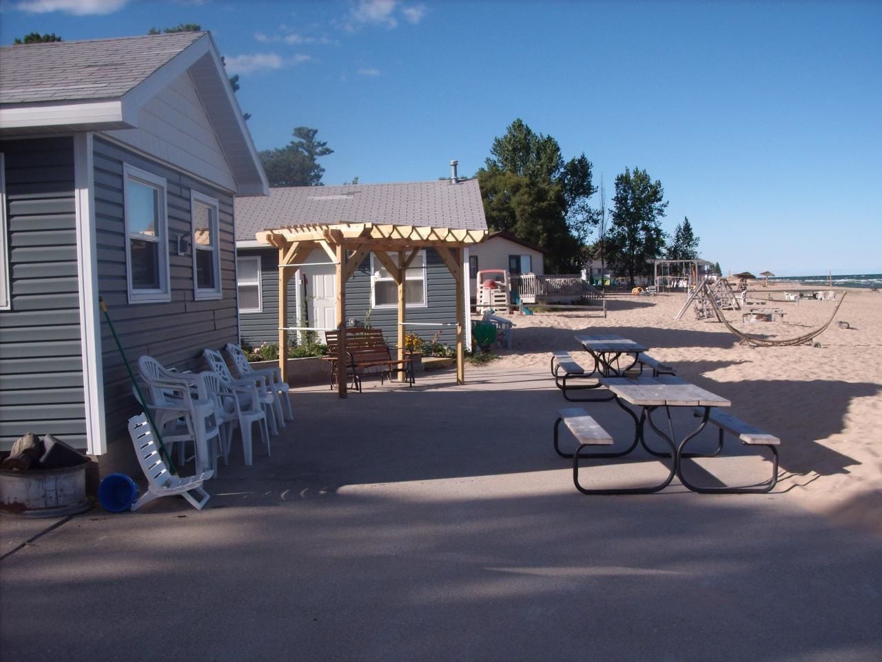 A beachside property with a covered patio, picnic tables, and outdoor seating.