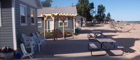 A beachside property with a covered patio, picnic tables, and outdoor seating.