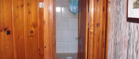 A wooden door leading to a bathroom with tiled walls and a shower curtain.
