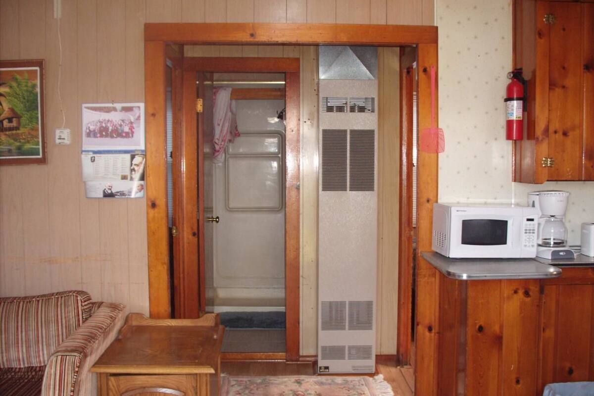 A compact living space with a kitchenette, a wooden door leading to a bathroom, and a small seating area.
