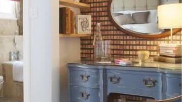 Un dormitorio con cama, cómoda, silla y espejo.