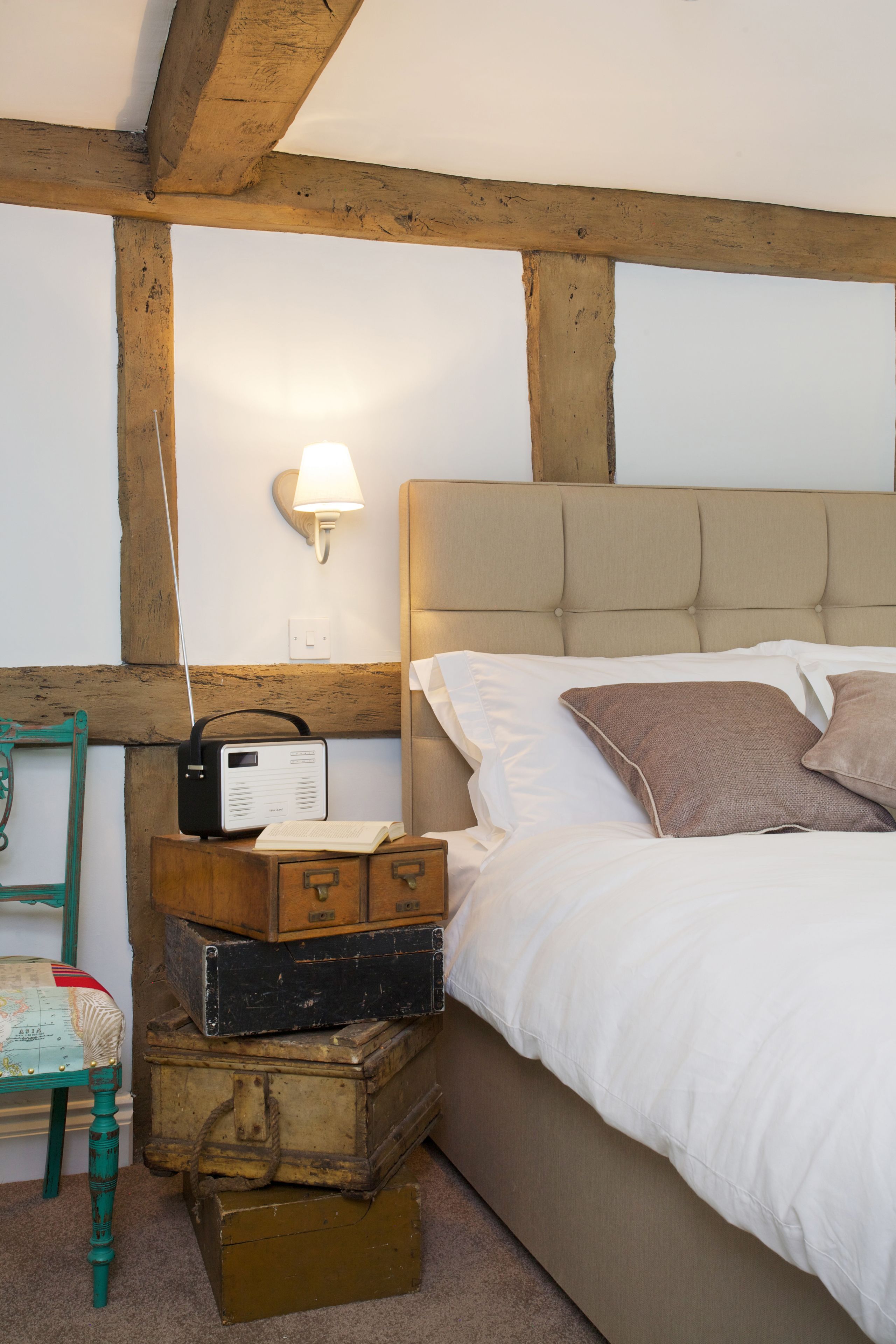 Een slaapkamer met een bed, een lamp en gestapelde koffers.