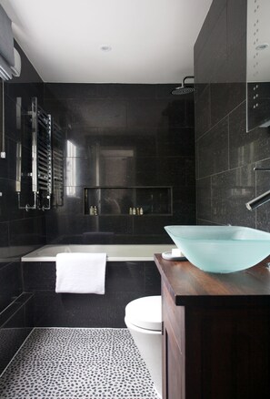 Een moderne badkamer met een wastafel van glas, een badkuip en een douche.