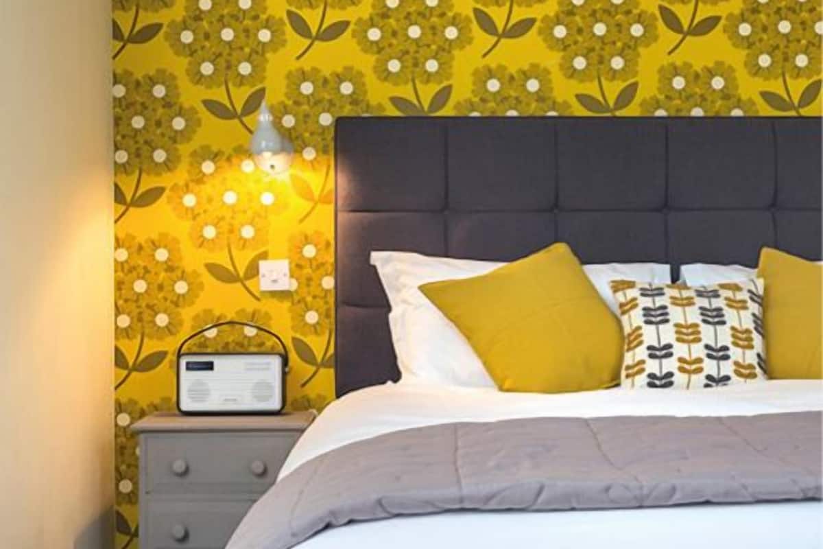 Un dormitorio con cama, mesita de noche y pared con estampado floral.