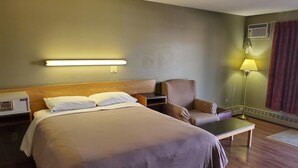 Ein Hotelzimmer mit Bett, Stuhl, Schreibtisch und Lampe.