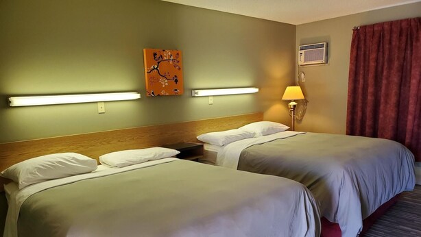 A hotel room with two beds, a wooden headboard, a wall-mounted artwork, a lamp, and a window with curtains. - Stars Inn & Suites Building B (Fort Saskatchewan)