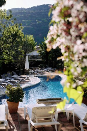 Zona de piscina con sillones de descanso y una planta en maceta.