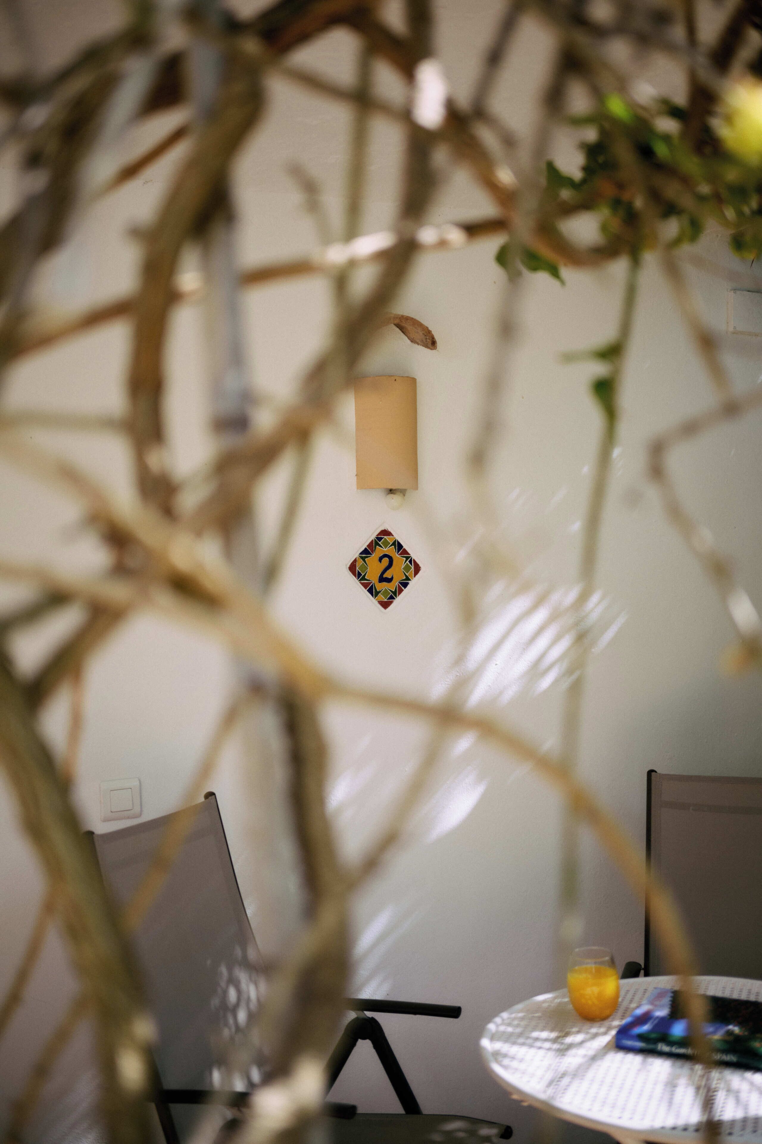 A room with a round table, a chair, a wall-mounted light fixture, and a small decorative item.