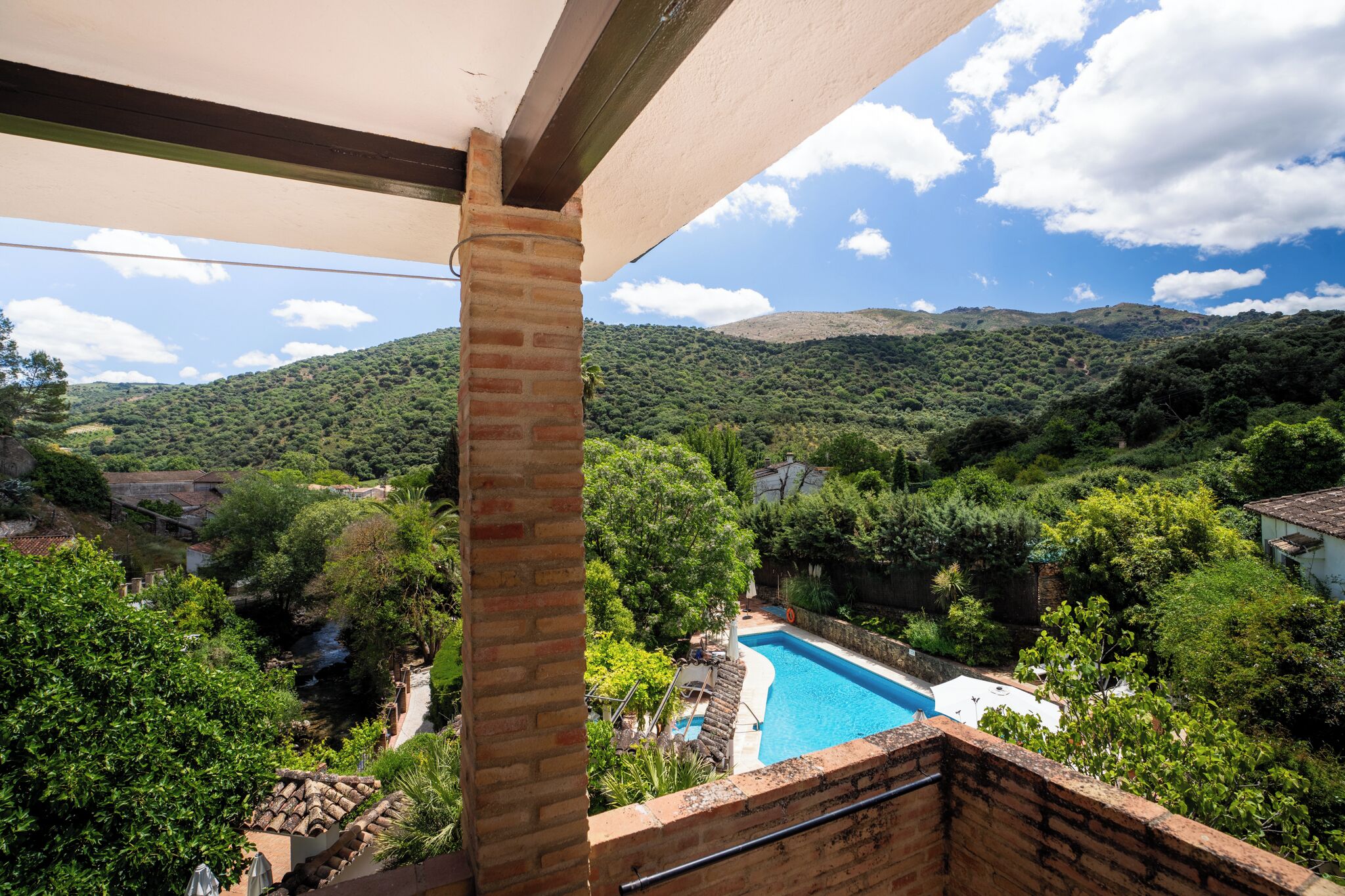 Vista de una piscina rodeada de abundante vegetación y colinas.