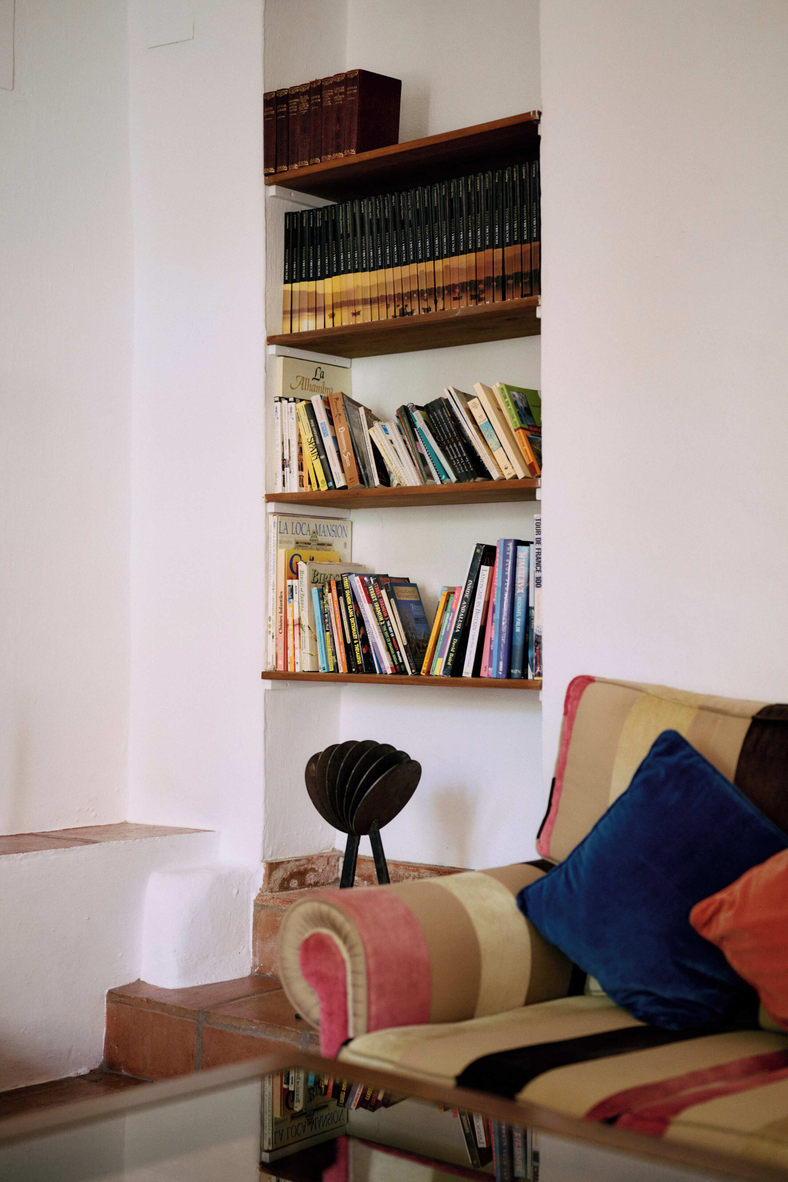 Un salon avec un canapé, une bibliothèque et une petite table.