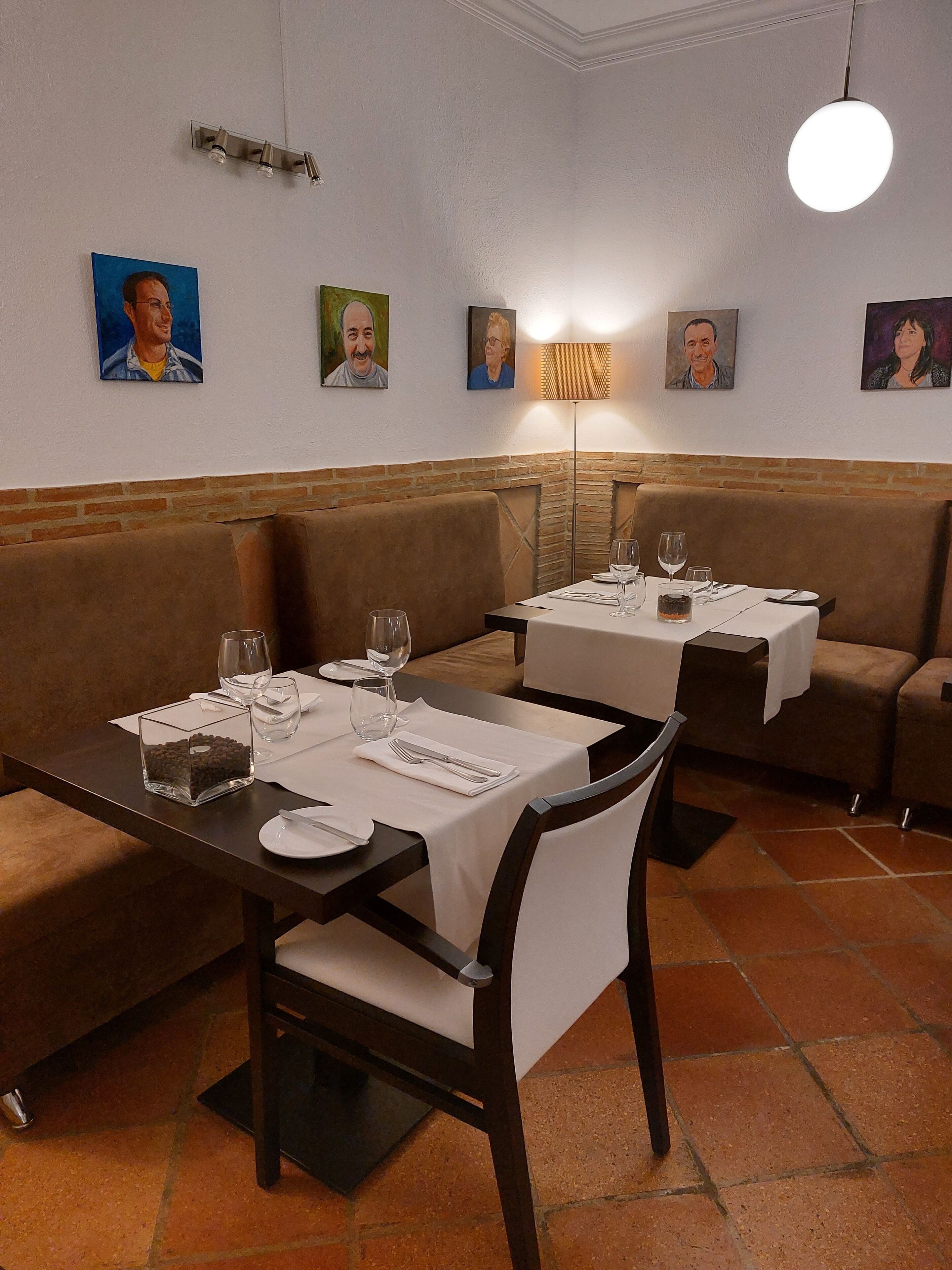 A dining area with booths and tables, each set with cutlery and glasses, and a lamp on the wall.