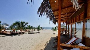 Un resort frente a la playa con estructuras de madera, palmeras y una vista despejada del océano.
