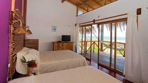 Una habitación con dos camas, televisión y vista a la playa.