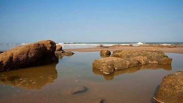 Uma praia com pedras grandes e águas calmas.